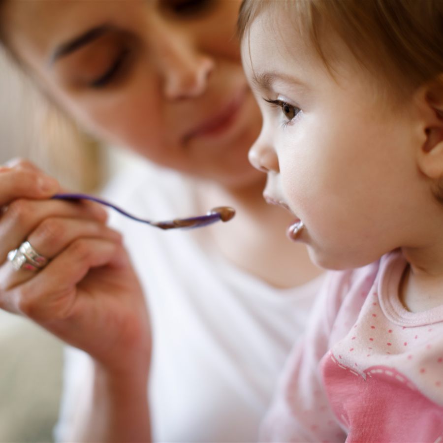 Mãe oferecendo comida ao bebê com uma colher